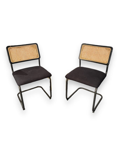 Two black chairs with woven backrests on a white background